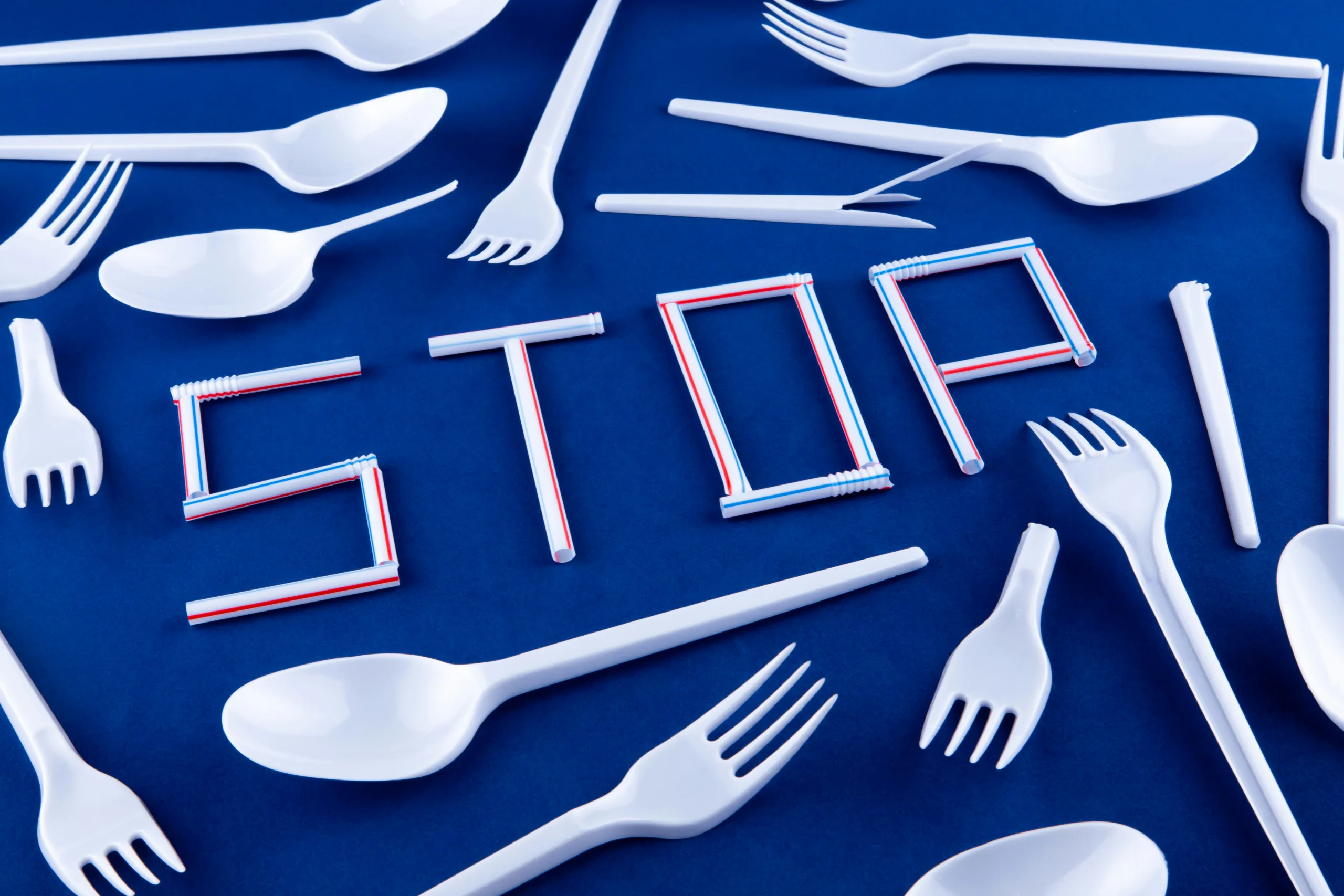 the word stop made out of plastic straws and spoons on a blue background